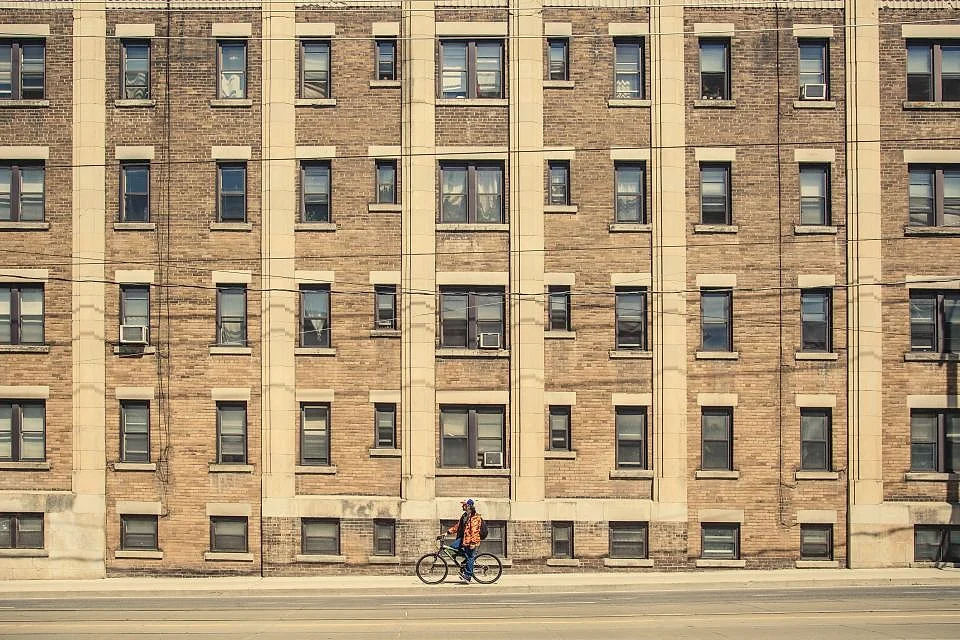 A brick apartment building on a city street with a cyclist passing