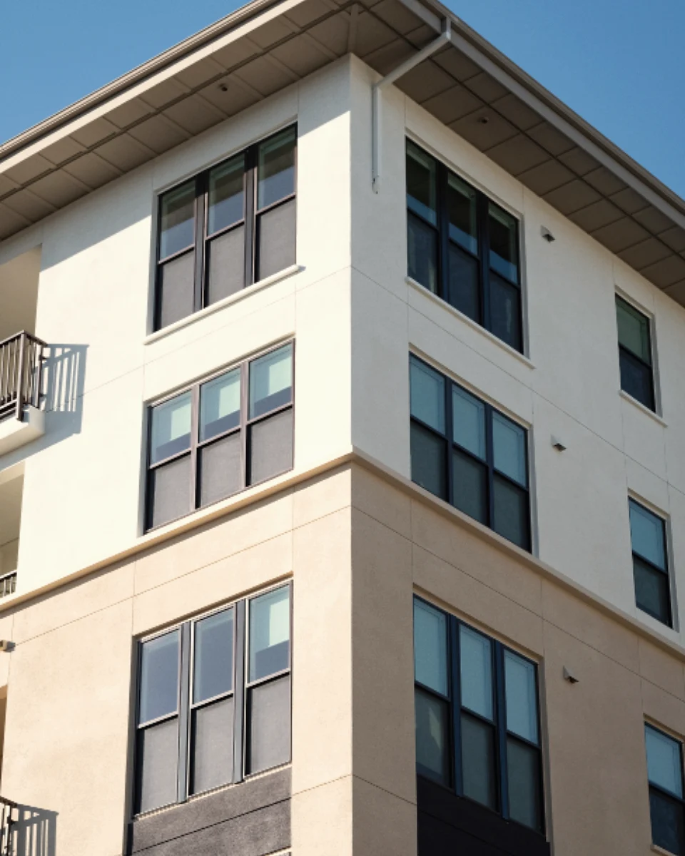 A modern white mid-rise apartment building with balconies