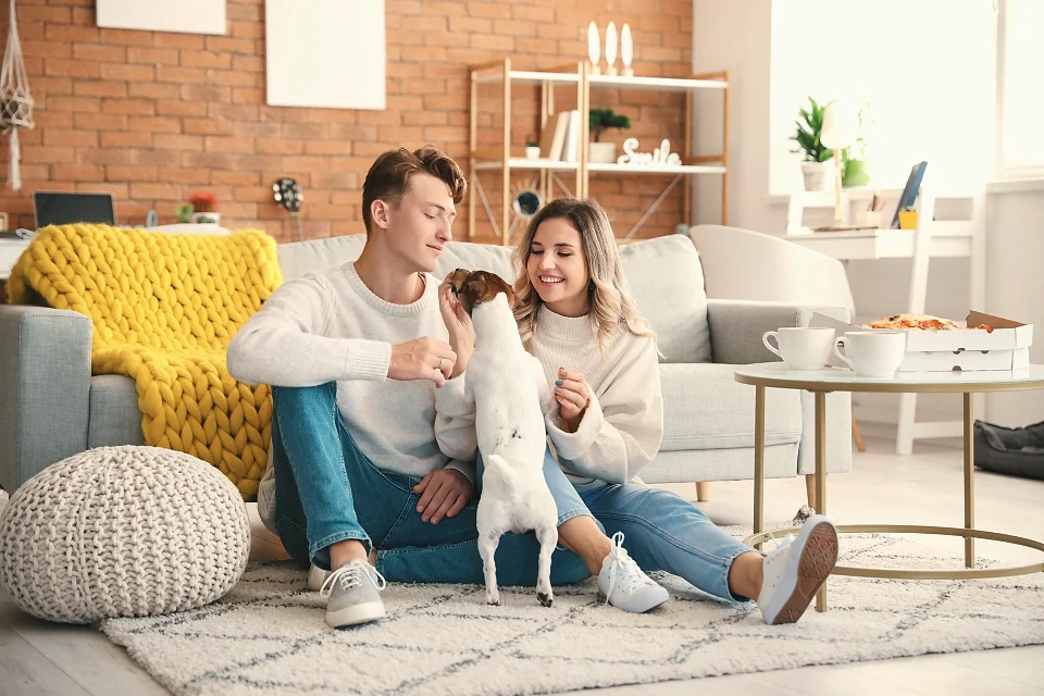 A couple on the floor of their new apartment with their puppy
